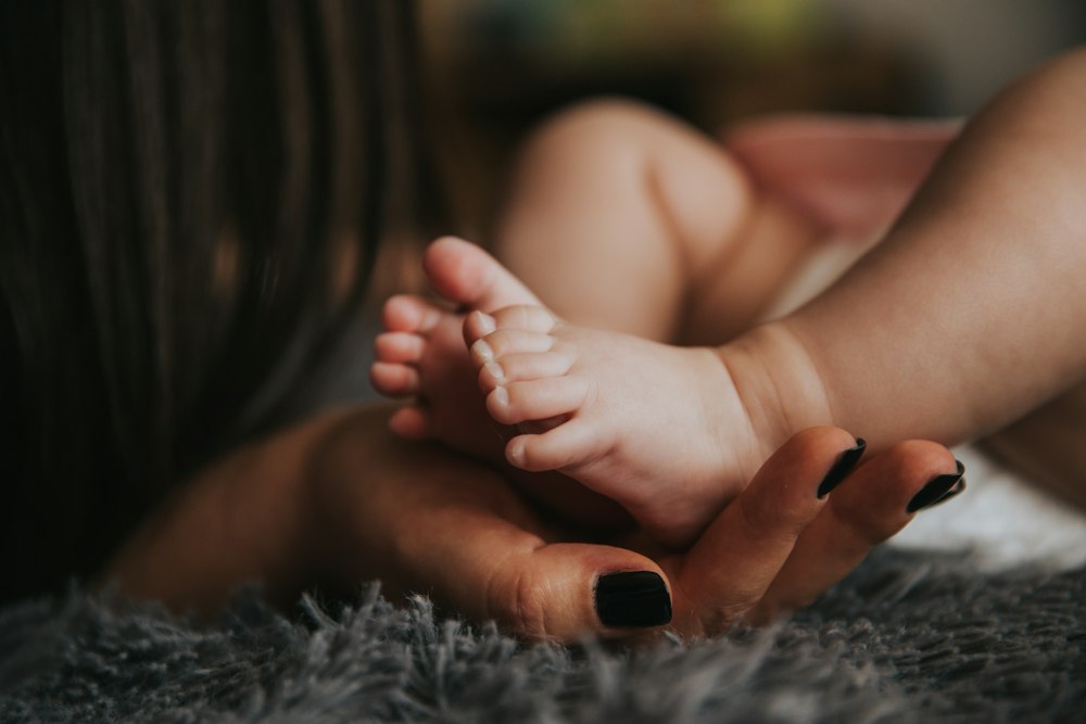 A newborn's feet held gently in an adult's hand